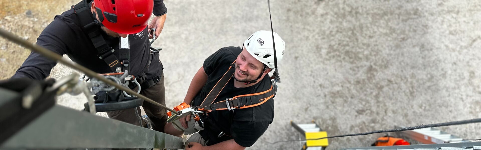 Looking down at two people hanging from ropes and harnesses